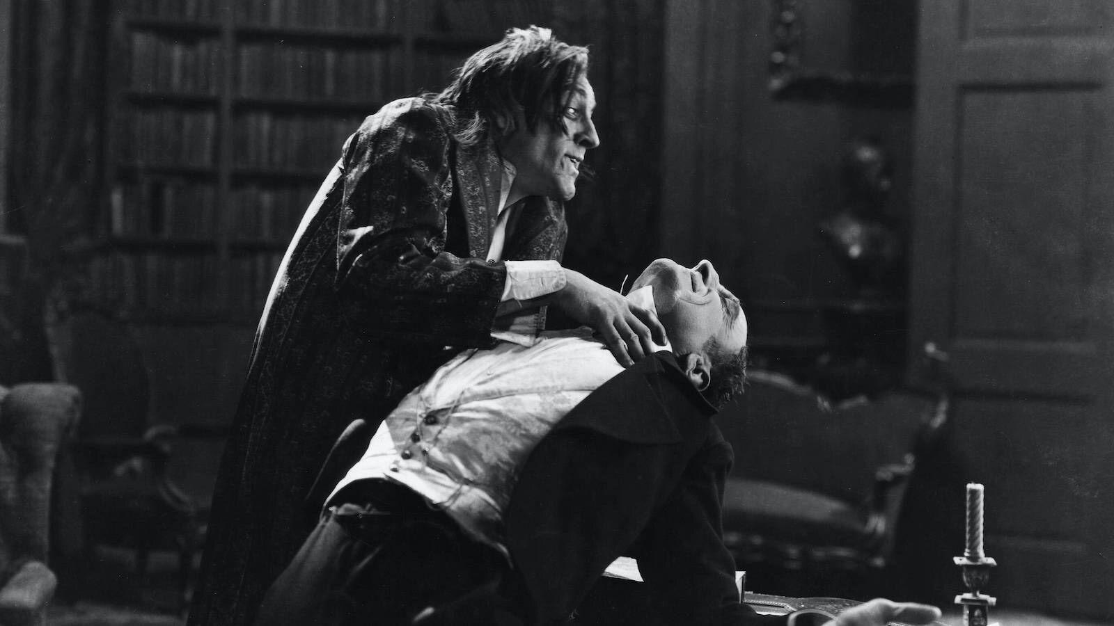Mr. Hyde leaning over Sir George Carewe in a black-and-white film still